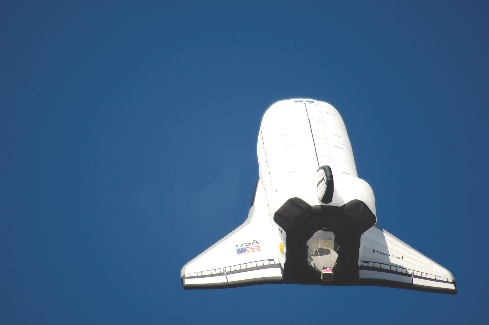 Space shuttle replica flying against a blue sky — historic image