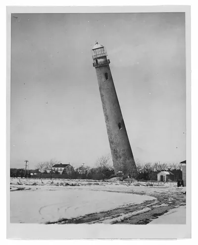 Leaning lighthouse tower above a snowy field, black and white photograph