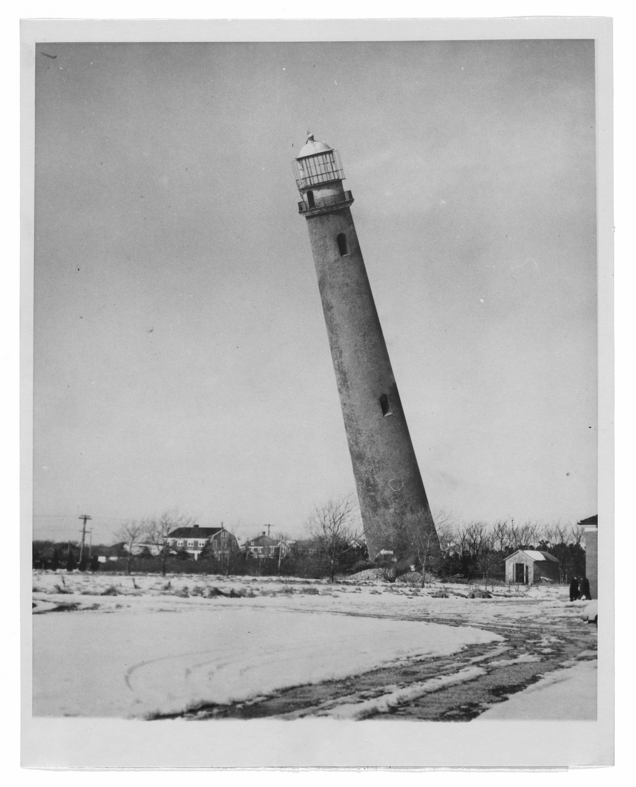 Leaning lighthouse tower above a snowy field, black and white photograph — historic photograph