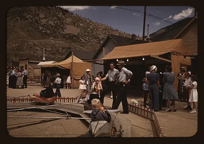 Children and tents at a county fair midway, Colorado