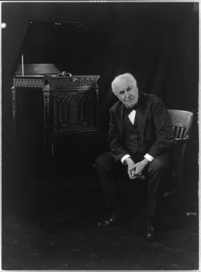 [Thomas Edison, seated beside phonograph]