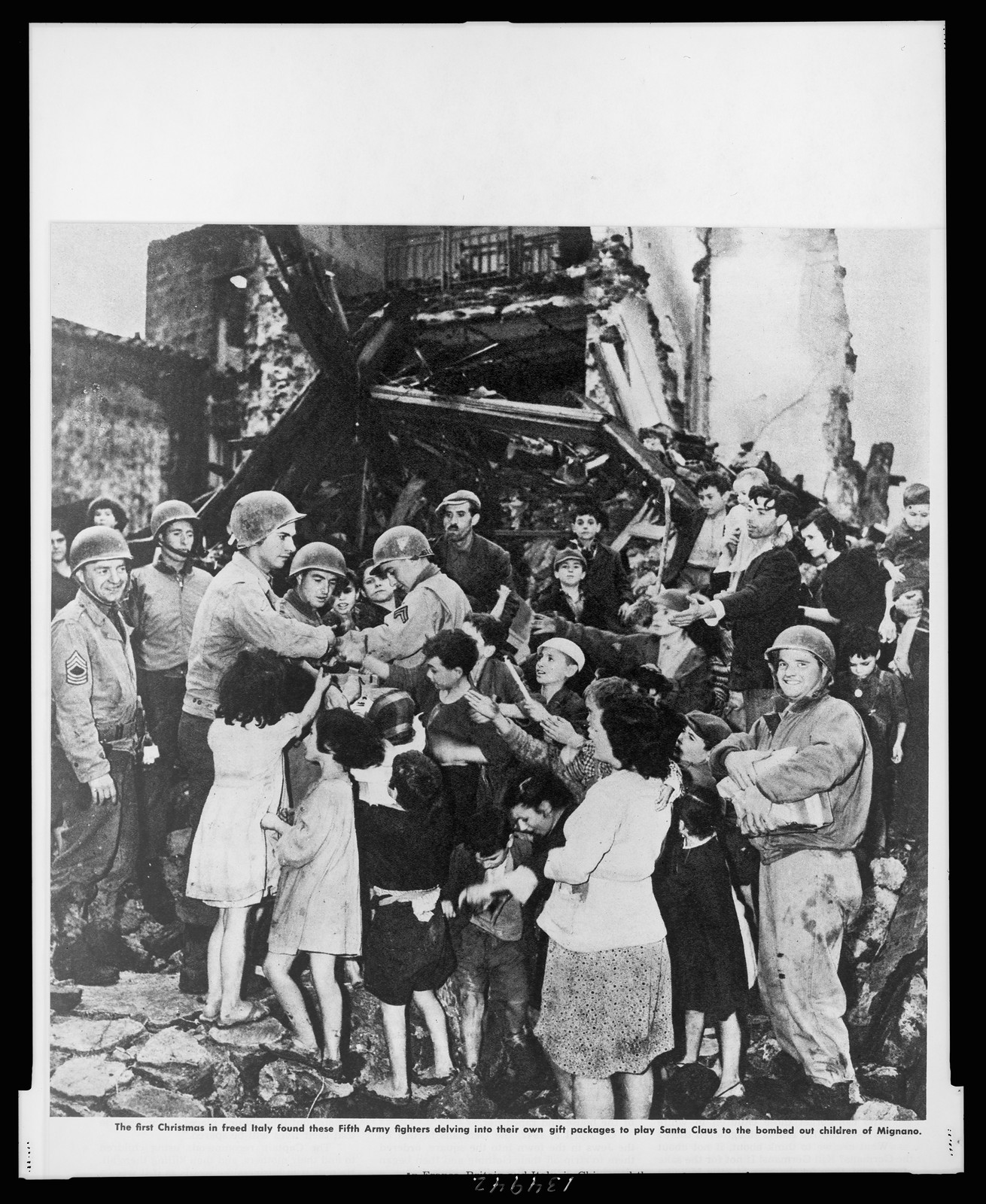 The first Christmas in freed Italy found these Fifth Army fighters delving into their own gift packages to play Santa Claus to the bombed out children of Mignano — historic print