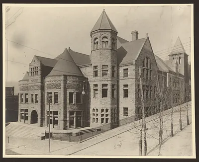 Stone civic building with turrets and tower, street view