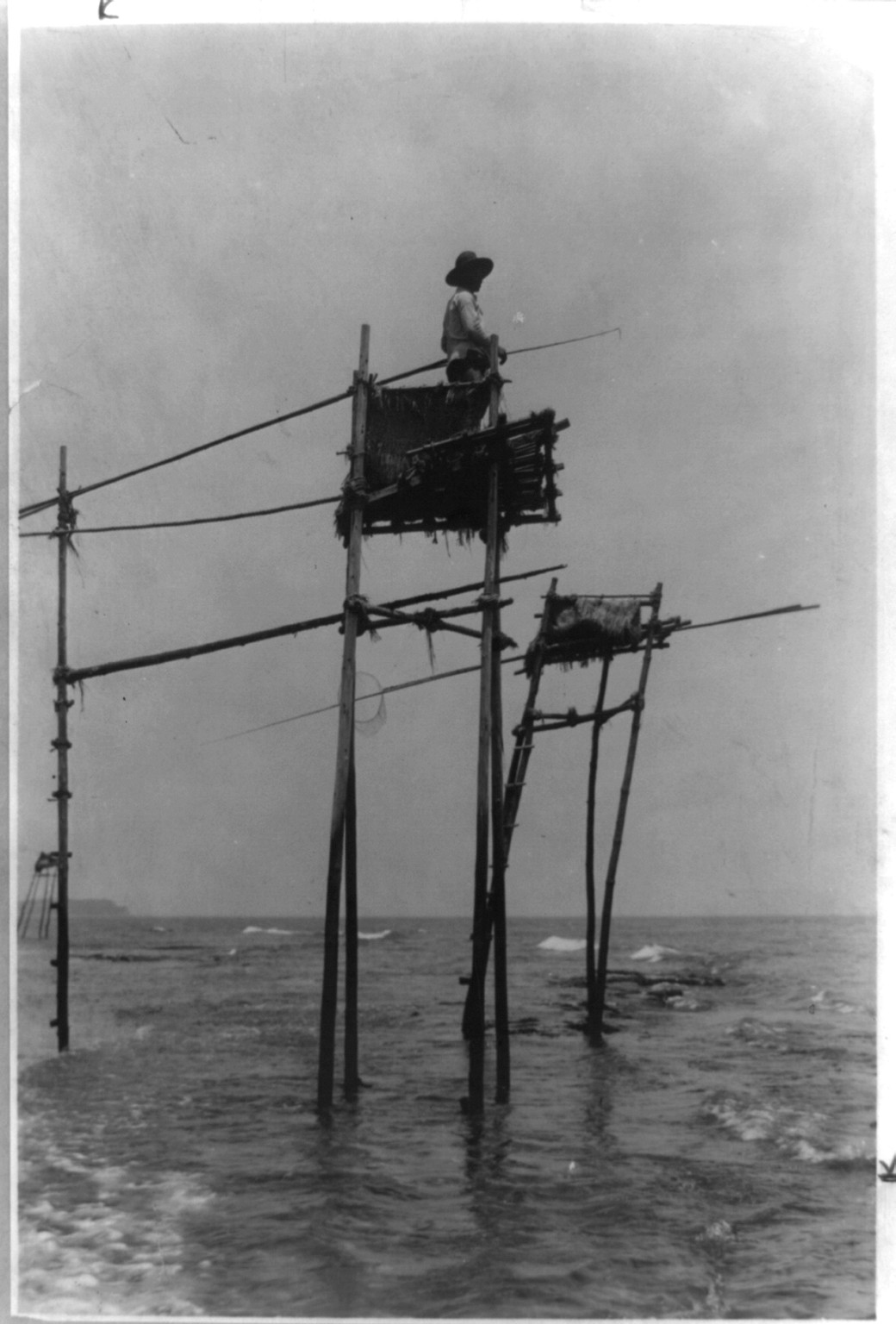 Fisherman in bamboo tower watching for fish, Kamakura, Japan, [between 1890 and 1923] — historic photograph