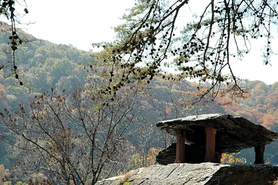 Stone slab shelter on rock above autumn wooded hills