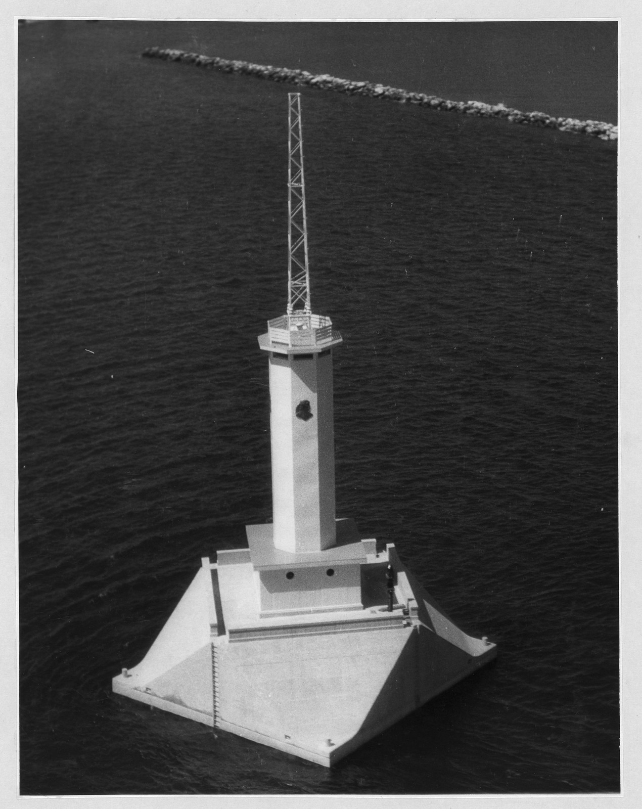 Concrete caisson lighthouse on open water with breakwater — historic image