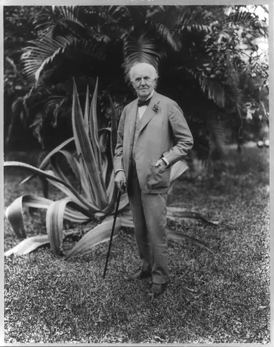 [Thomas Alva Edison, 1847-1931, full-length portrait, standing, facing left, in garden, cactus in background]