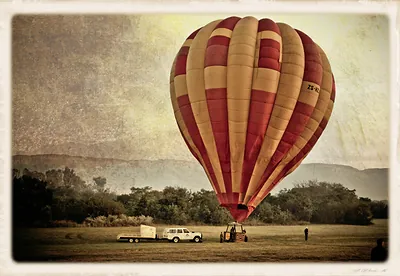 Hot air balloon inflating on a grassy field with trailer