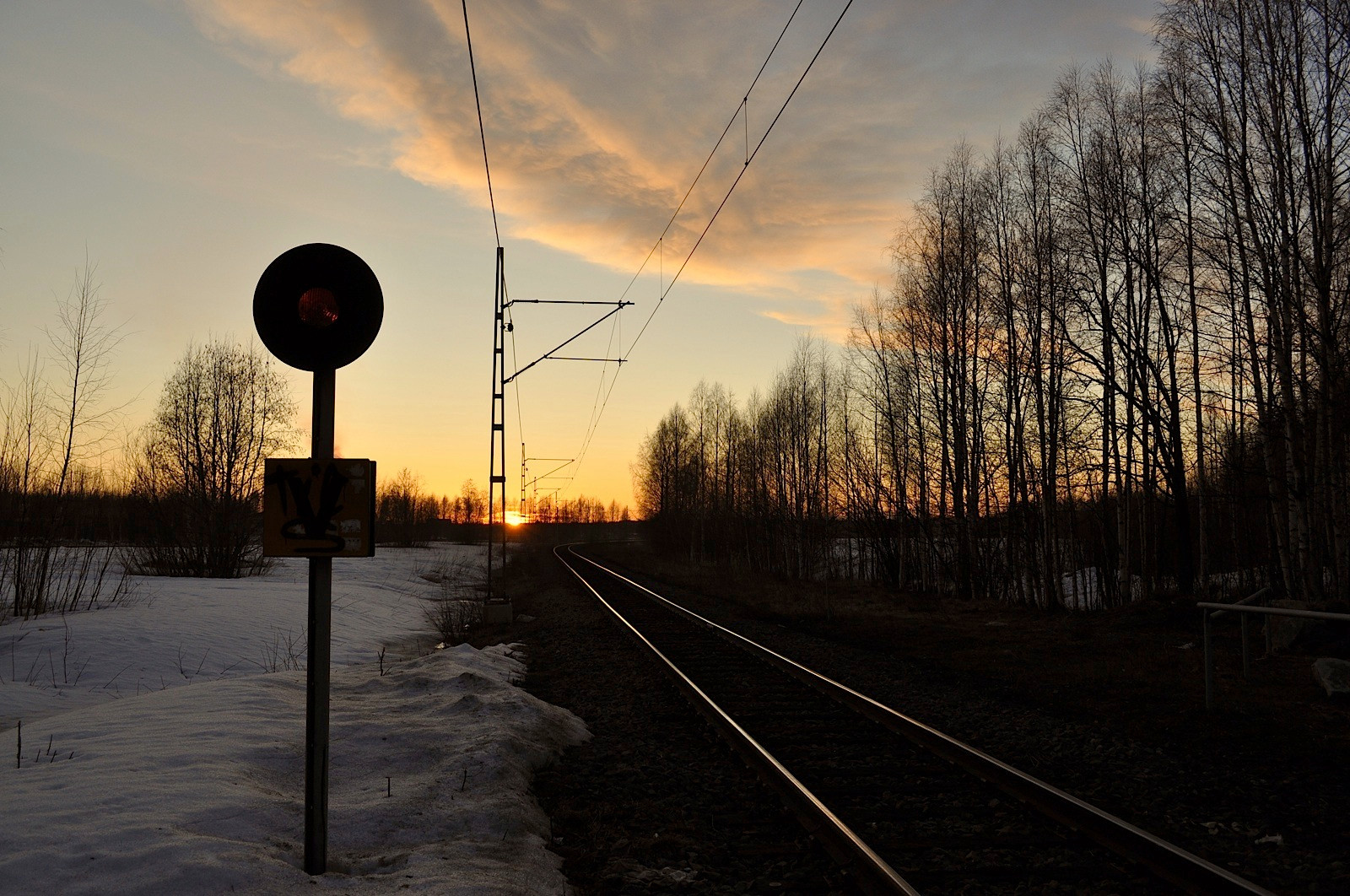 Railroad track at sunset with signal and overhead wires — historic image