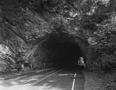 Two-lane road through a rock tunnel, black and white photograph