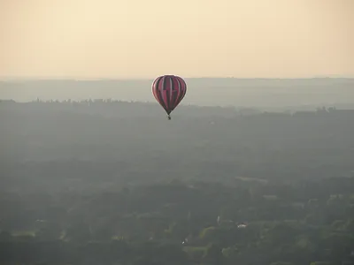 Hot air balloon over hazy countryside at dusk