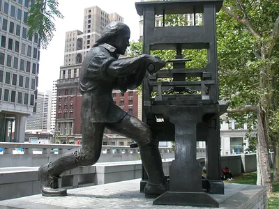 Bronze statue of a man working a printing press