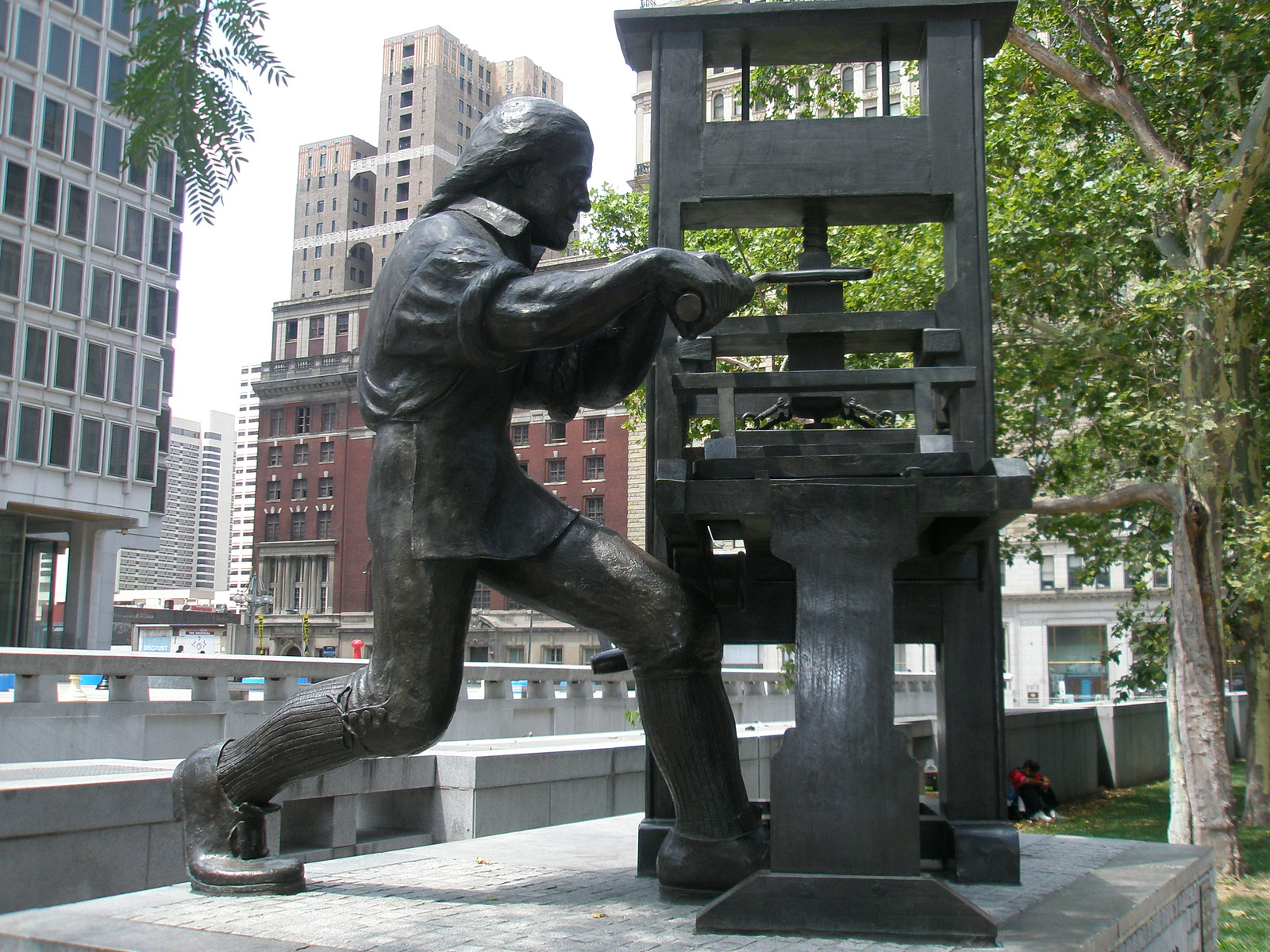 Bronze statue of a man working a printing press — historic print