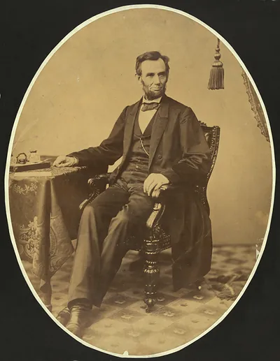 Seated bearded man in suit, oval sepia studio portrait