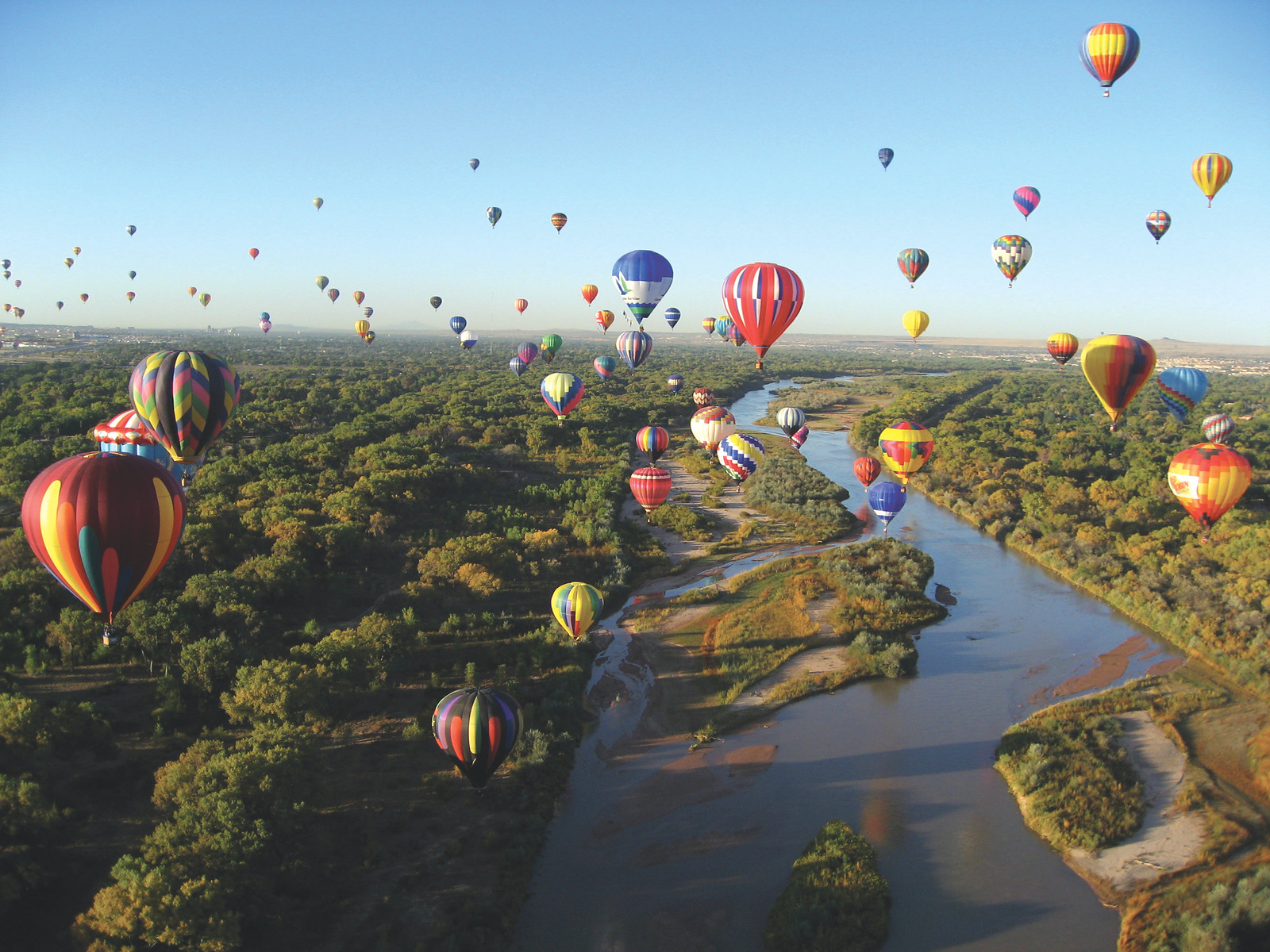 Hot air balloons over a river and cottonwood trees — historic image