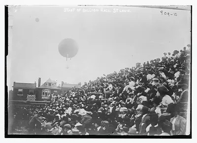 Crowd in stands, balloon overhead, at start of balloon race, St. Louis