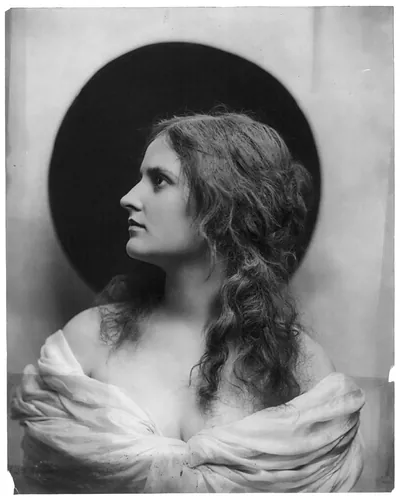 [Young woman modeling: head and shoulders, facing left, wearing low-cut dress]