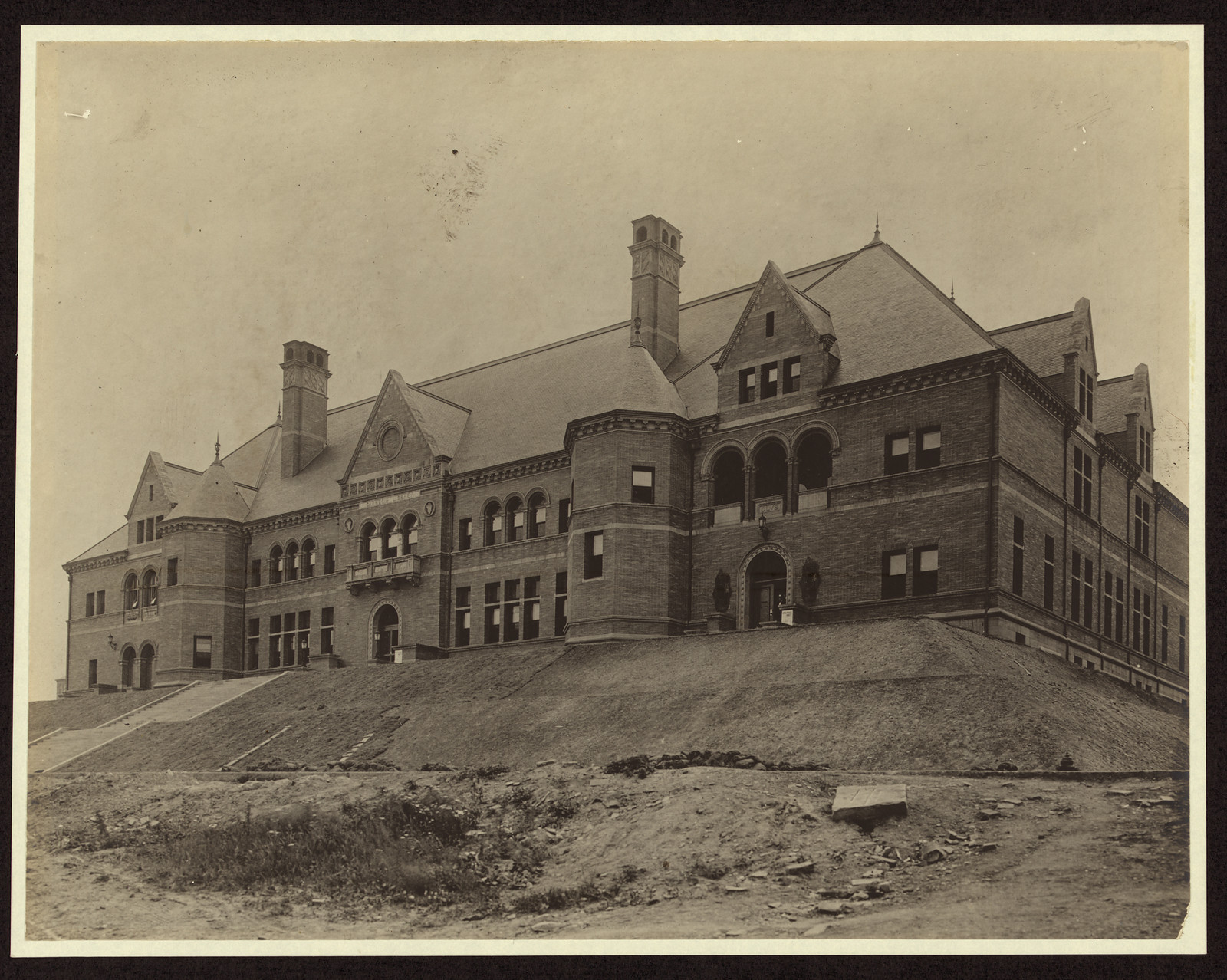 Large brick public building on a grassy hill, sepia photograph — historic photograph