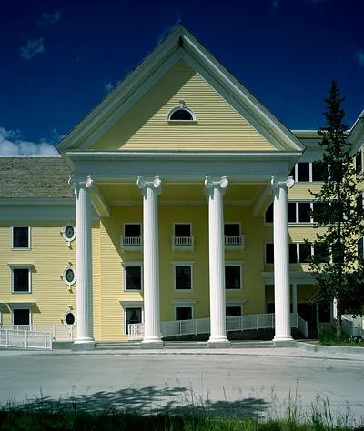 Yellow hotel with white columns and portico under blue sky