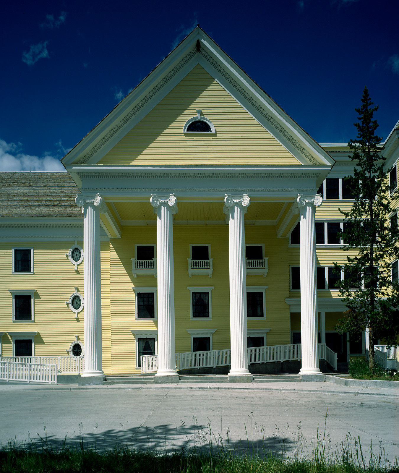 Yellow hotel with white columns and portico under blue sky — historic image