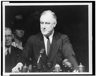 [Franklin D. Roosevelt, half-length portrait, standing, facing left, speaking into microphones]