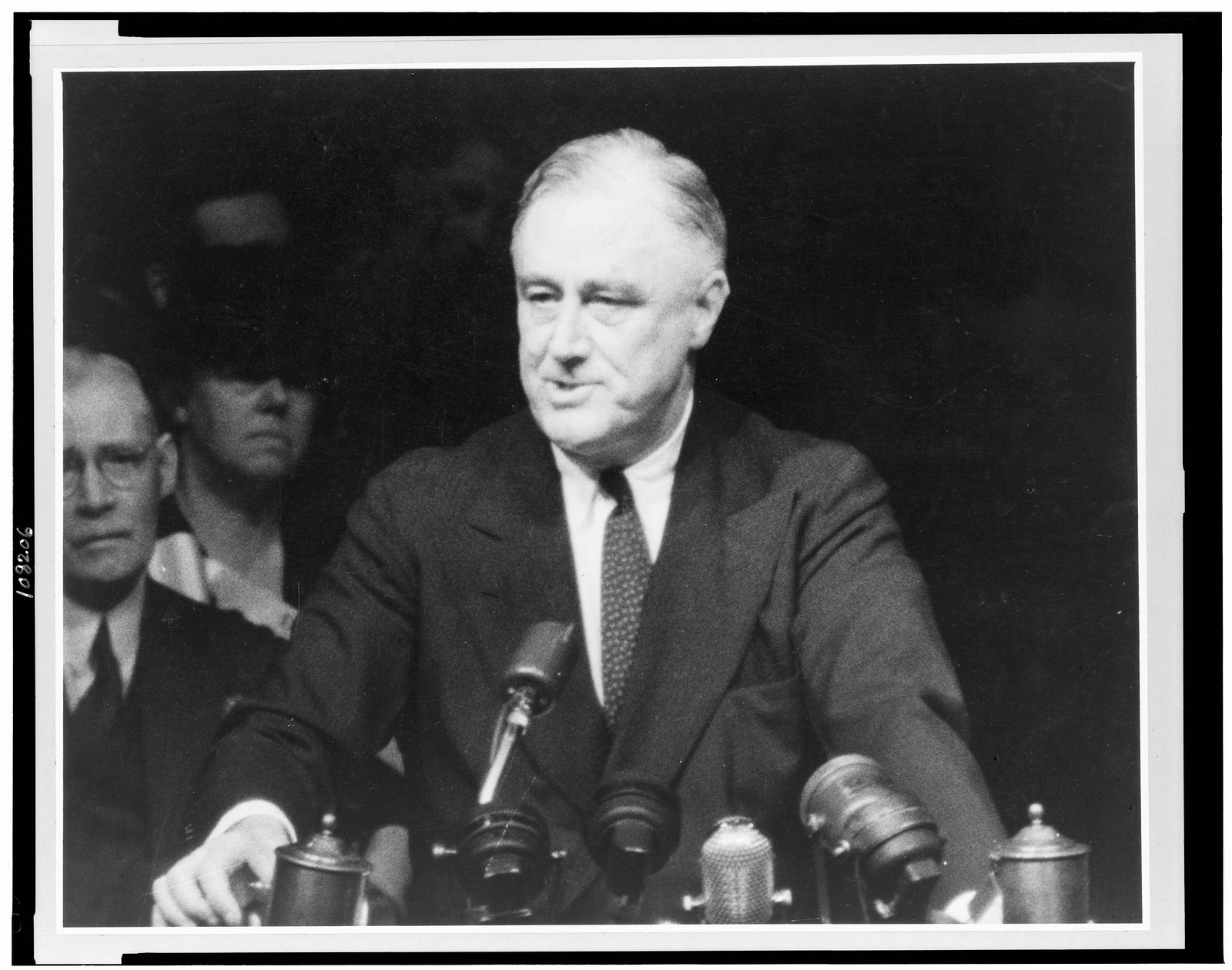 [Franklin D. Roosevelt, half-length portrait, standing, facing left, speaking into microphones], [ca. 1940] — historic photograph