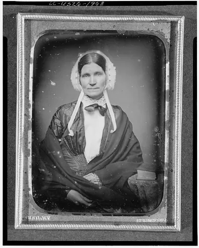 [Eunice Fiske Durfee, three-quarter length portrait of a woman, facing front, seated next to table with tablecloth; large book on table]