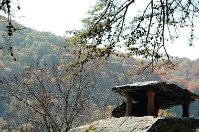 Stone rock shelter on rocky outcrop with autumn forest
