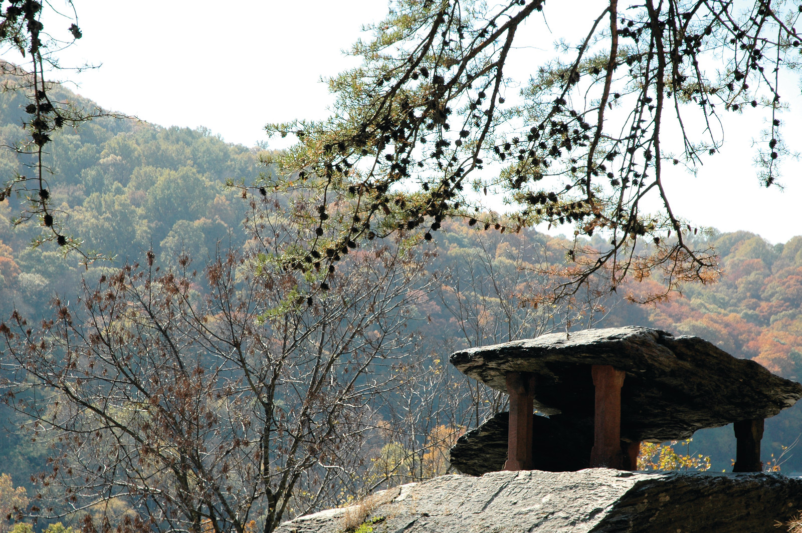 Stone rock shelter on rocky outcrop with autumn forest — historic image
