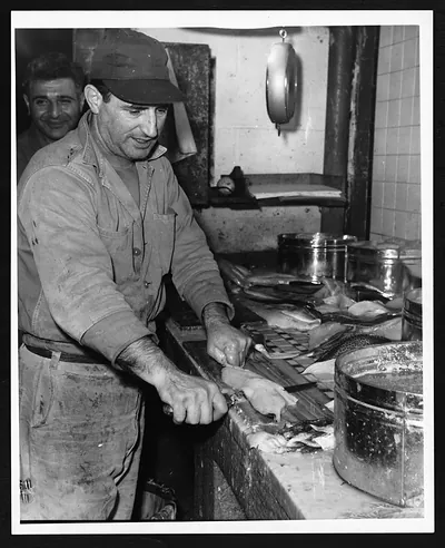 Man skinning fish at a market counter