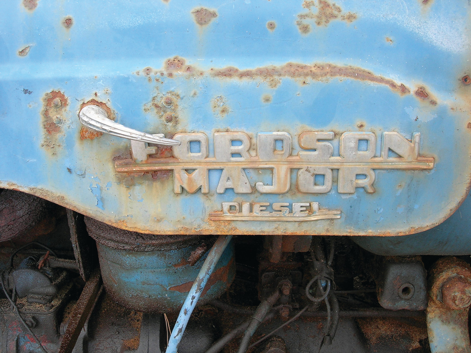 Rusty blue Fordson Major Diesel tractor badge close-up — historic image
