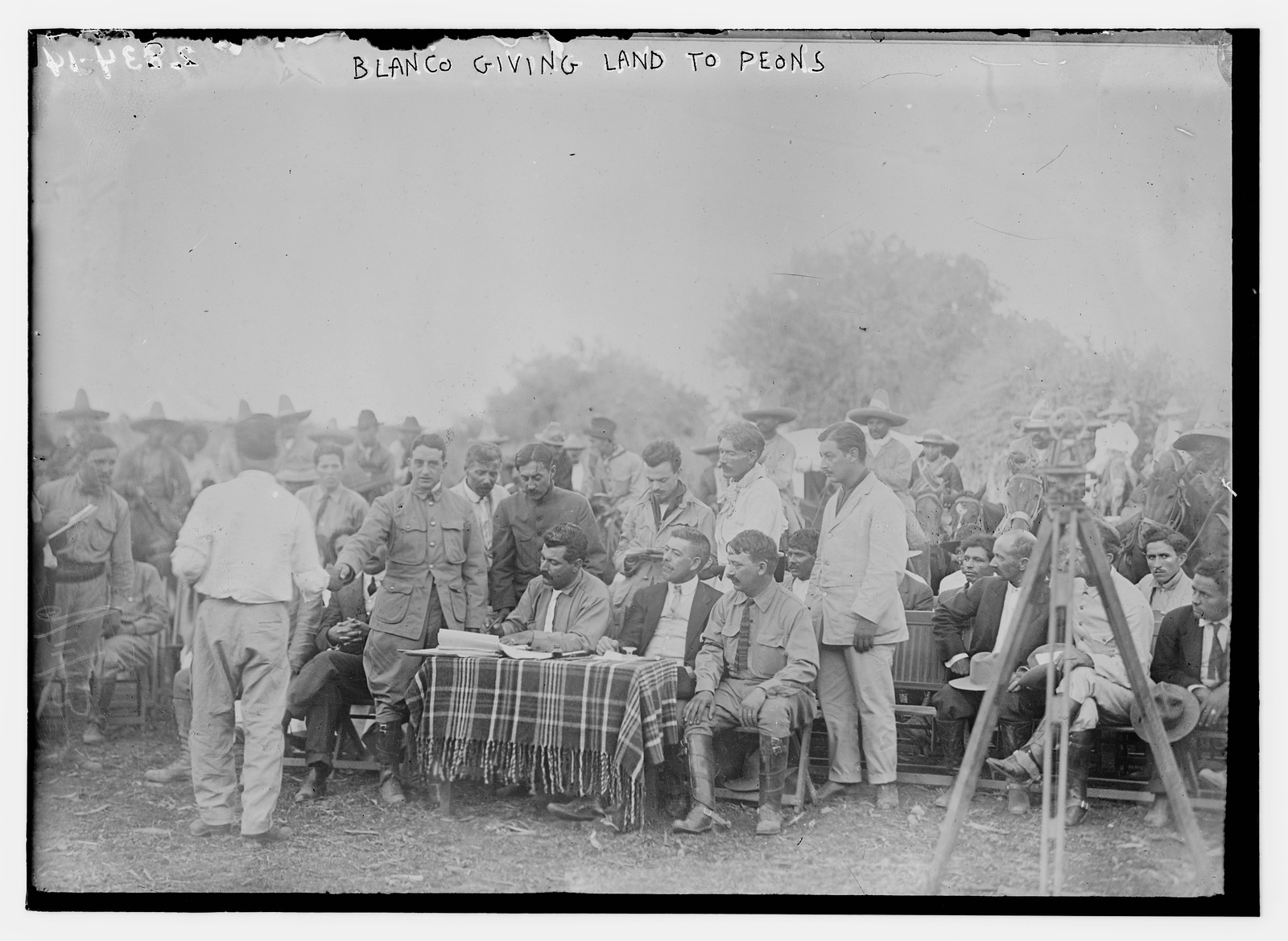 Blanco giving land to Peons at table in field, n/a — historic photograph