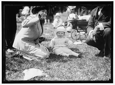 Woman and toddler in white hat on park lawn