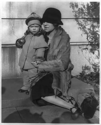 [Alice (Roosevelt) Longworth, 1884- , full-length portrait, on her 43rd birthday, seated on step with her 2 year old daughter Paulyna, facing left]