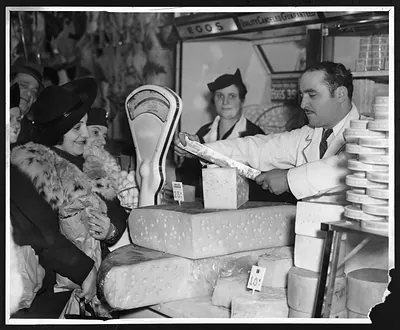Market vendor serving a customer at a cheese counter