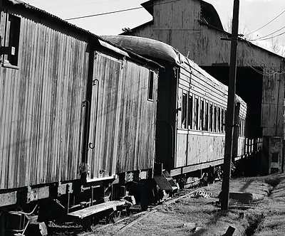 Old passenger rail cars beside a corrugated metal shed