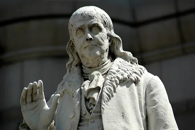 Marble statue of Benjamin Franklin with raised hand