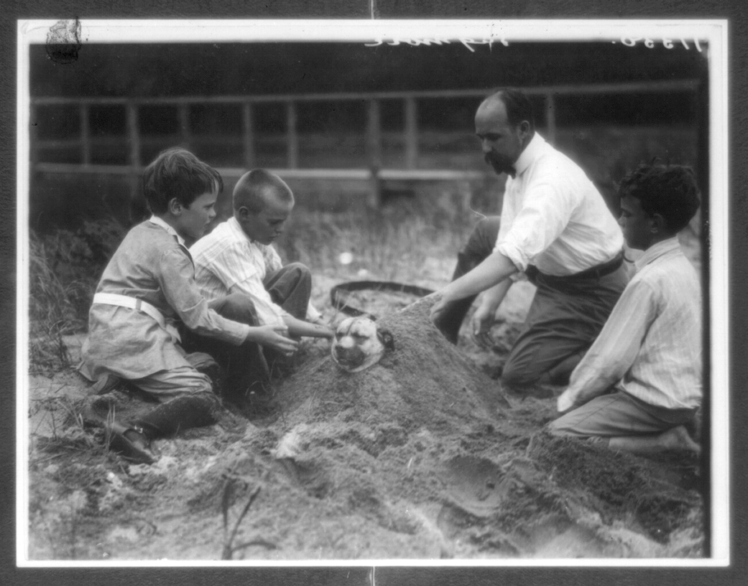 Theo Roosevelt's children burying a dog in the sand, c1904. — historic photograph