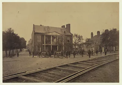 Hotel with cannons and soldiers beside railroad tracks
