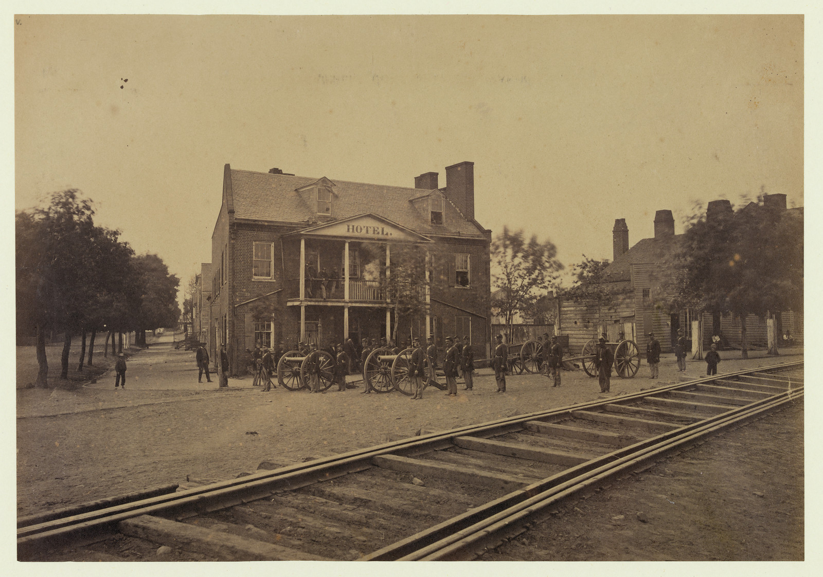 Hotel with cannons and soldiers beside railroad tracks — historic image