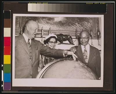 [Matthew Henson shows President Eisenhower the location of the North Pole on a globe at the White House while his wife, Lucy Henson, watches]