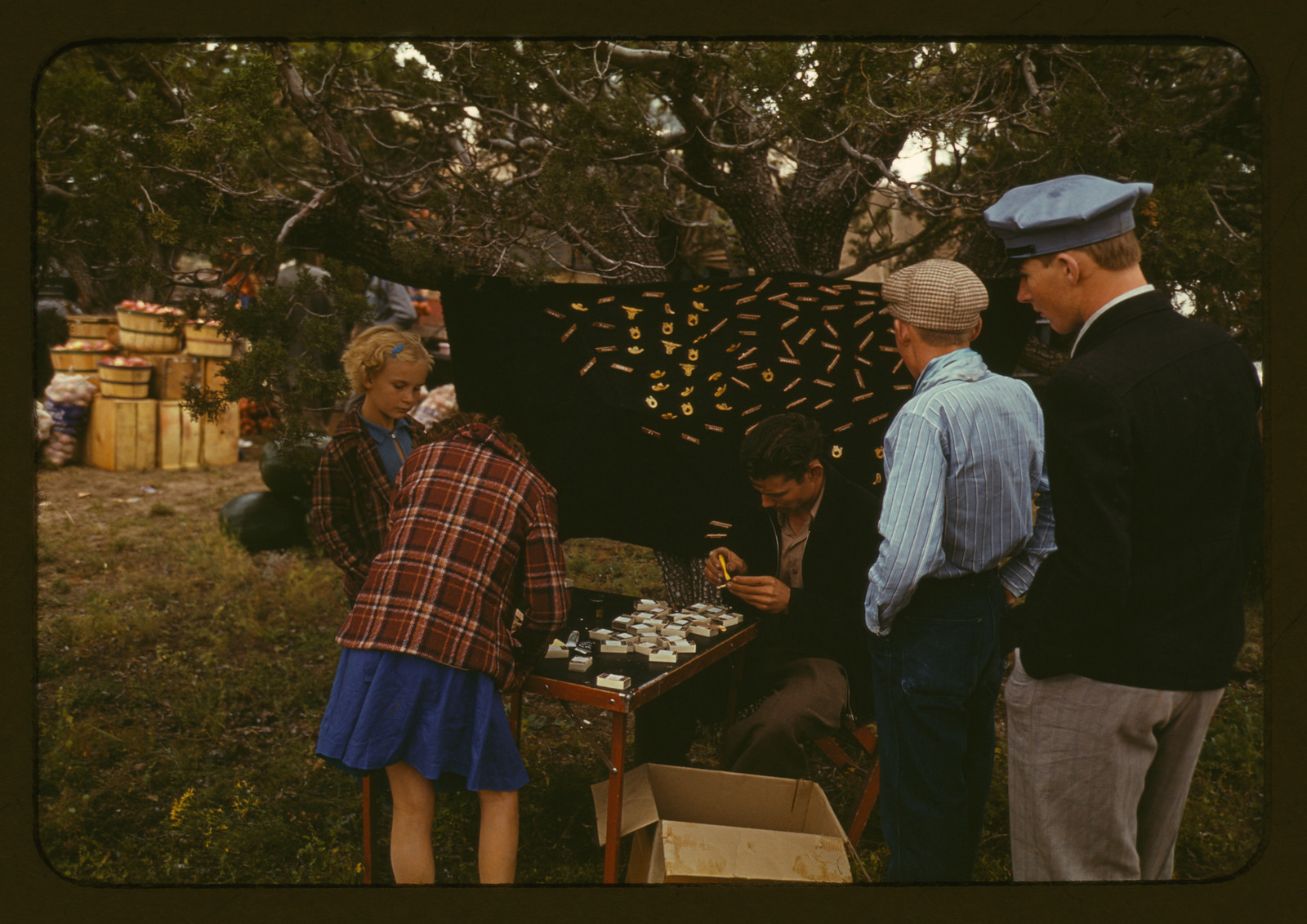 Vendor selling initial pins at an outdoor fair stall — historic image