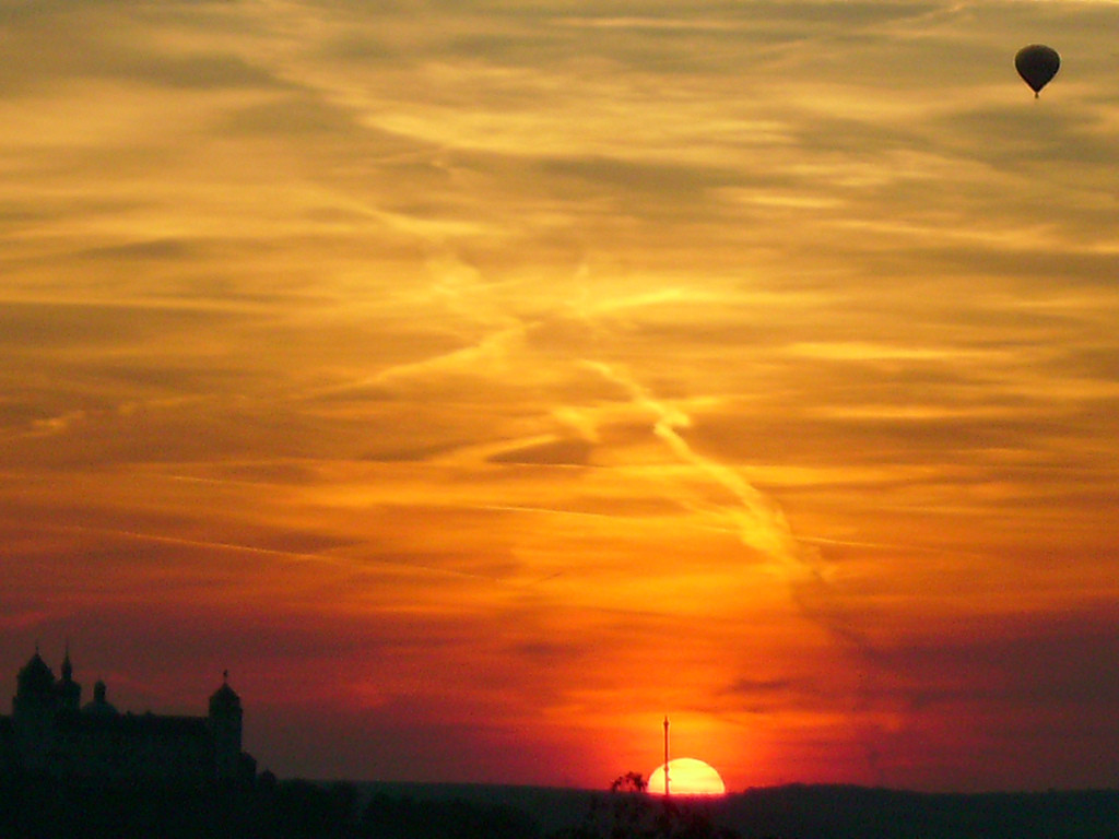 Sunset over silhouetted church with hot air balloon — historic image