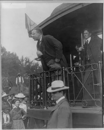 [Theodore Roosevelt, full, standing, speaking on train platform, left profile]