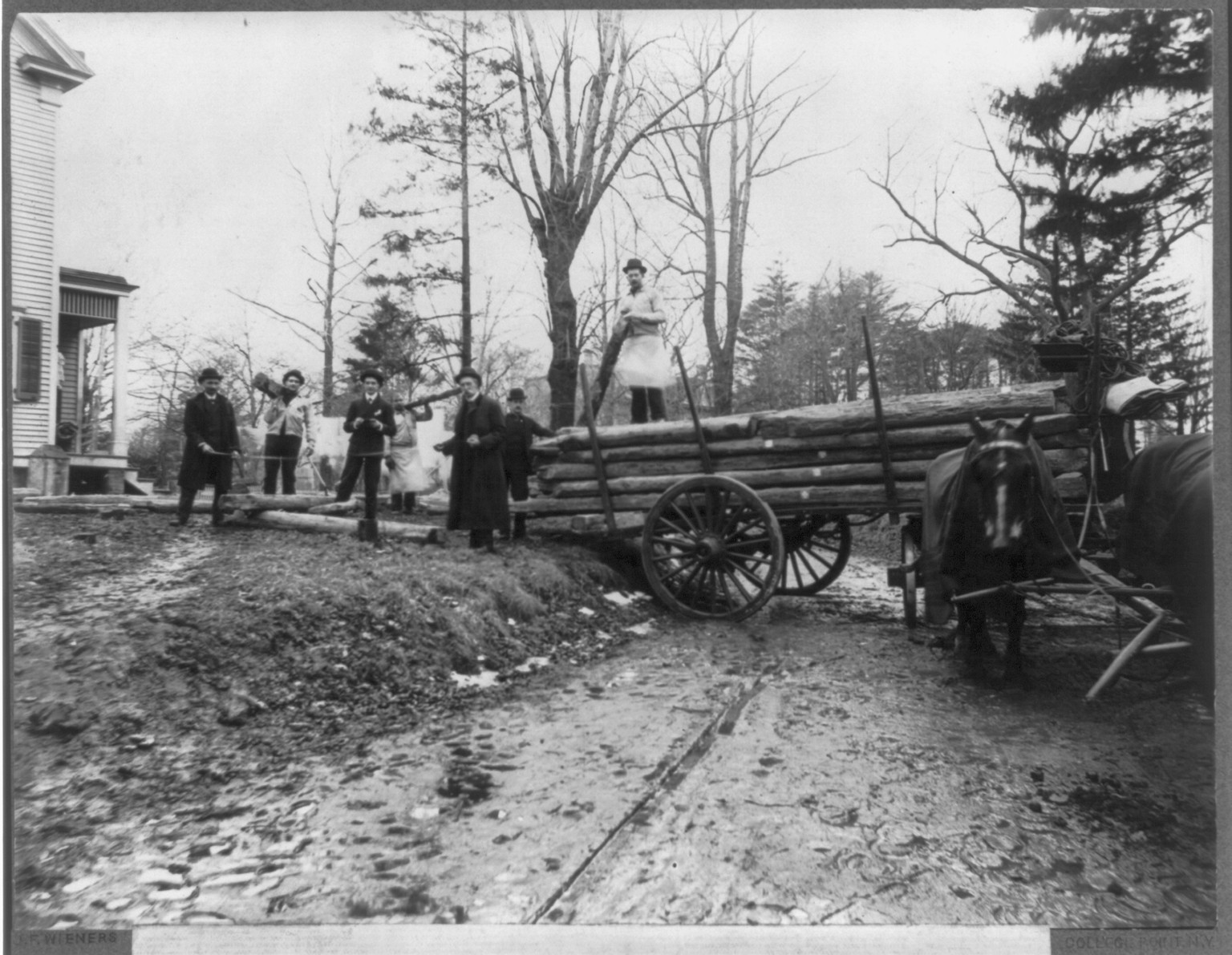 [Men loading logs on a horse-drawn wagon, from the original Abraham Lincoln log cabin, at College Point, N.Y., on Feb. 21, 1906, to be re-erected on the Lincoln Farm at Hodgenville, Kentucky, the birthplace of Lincoln], c1906. — historic photograph