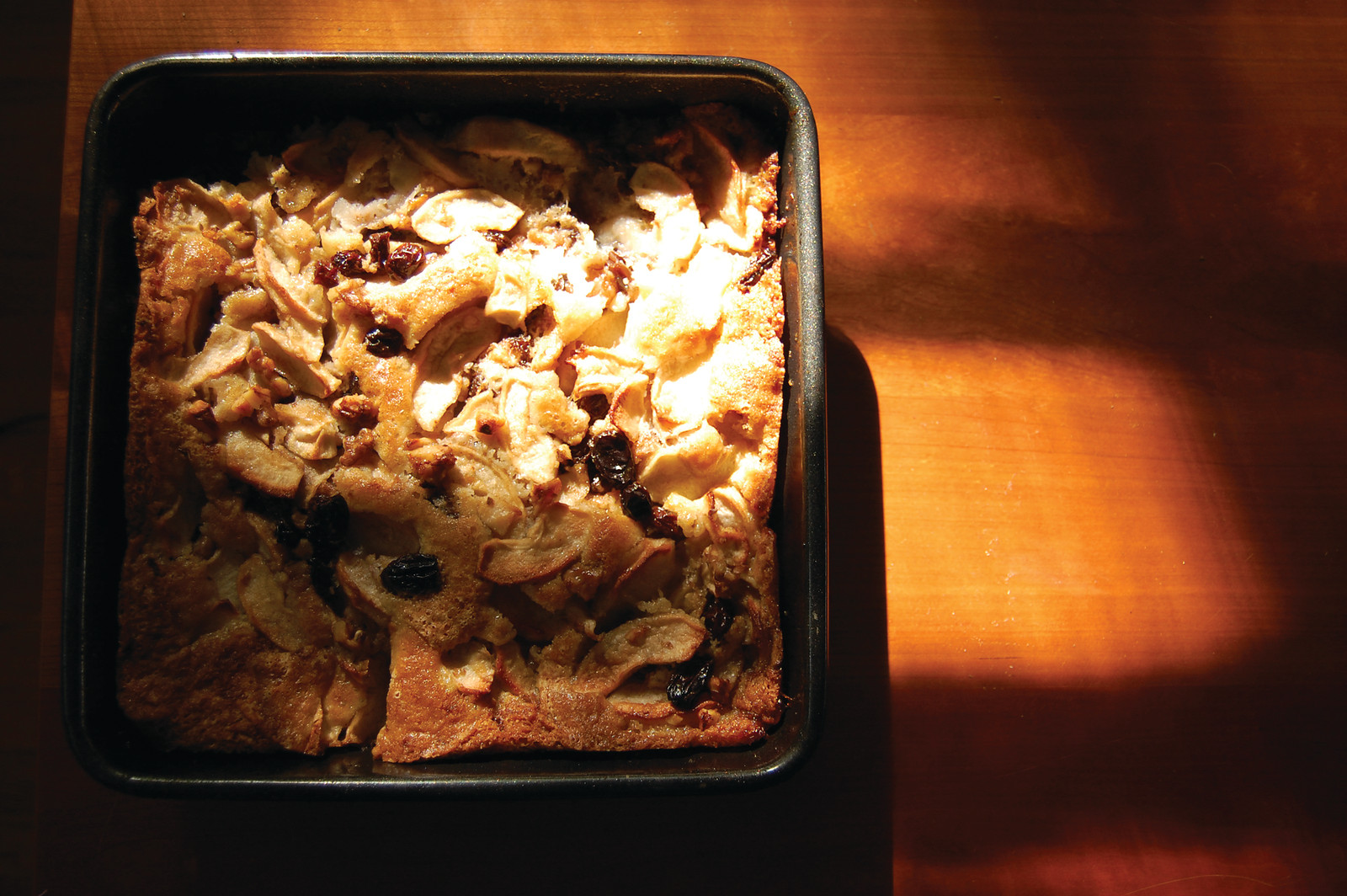 Apple bread pudding with raisins in square baking pan — historic image