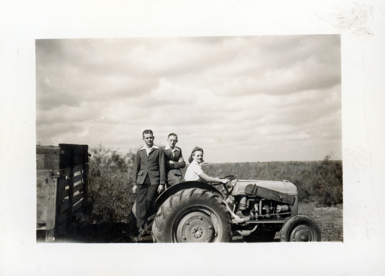 Young woman driving a vintage tractor with two men — historic image