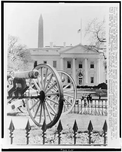 [Front facade of White House with flag at half-mast in honor of those who lost their lives on the USS Thresher; Civil War cannons in foreground]