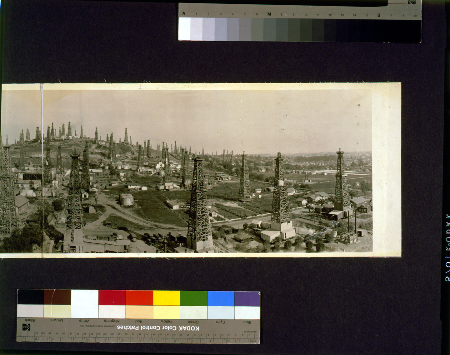 Panoramic view of oil derricks over a town — historic image