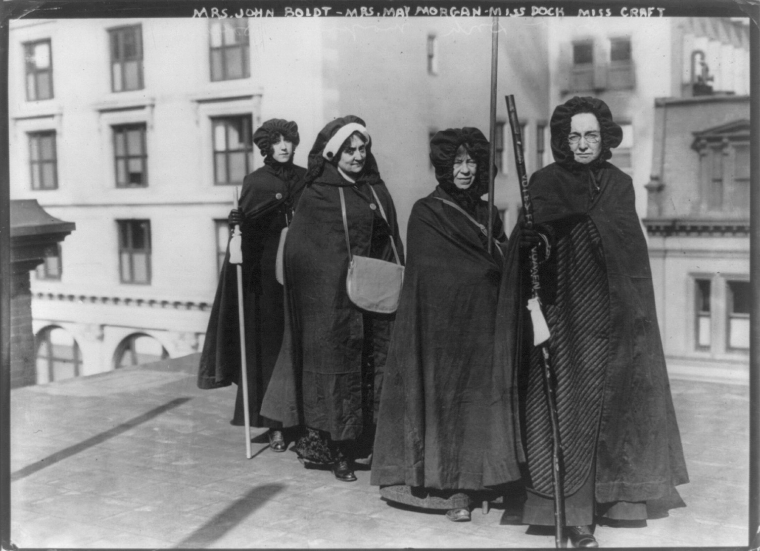 Mrs. John Boldt, Mrs. May Morgan, Miss Dock and Miss Craft [holding Votes for Women" staff]", 1913 Feb. 6. — historic photograph